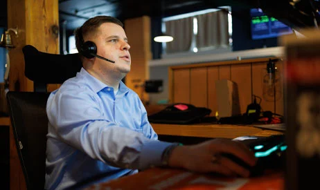A support technician on a headset working at a multi-monitor desk
