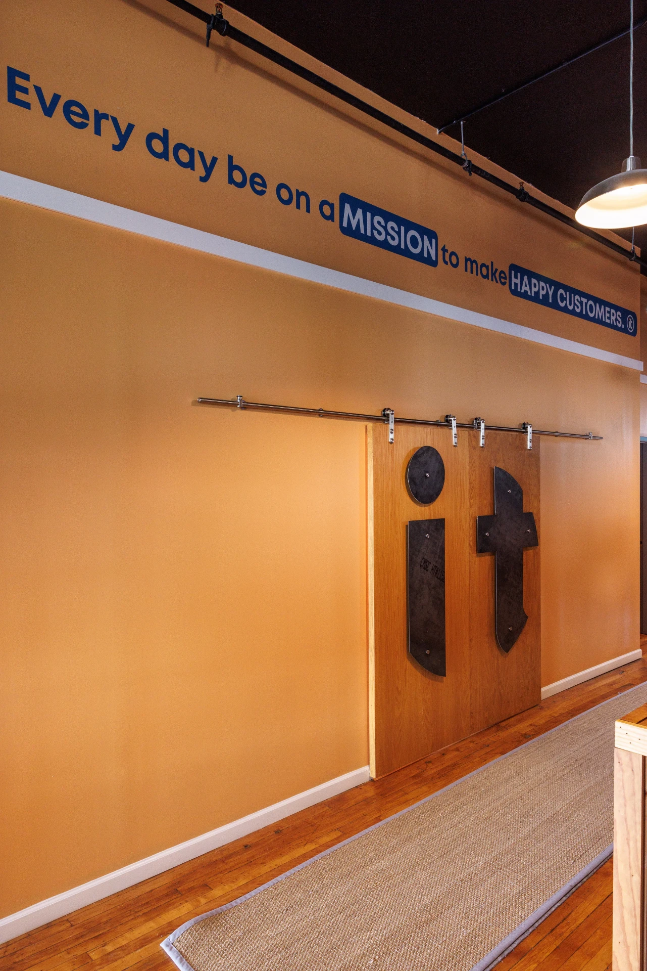 The IT Company Knoxville office hallway with the 'Every day be on a mission to make happy customers' wall mural