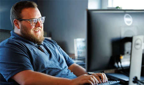 An IT engineer smiling while working at a desktop workstation